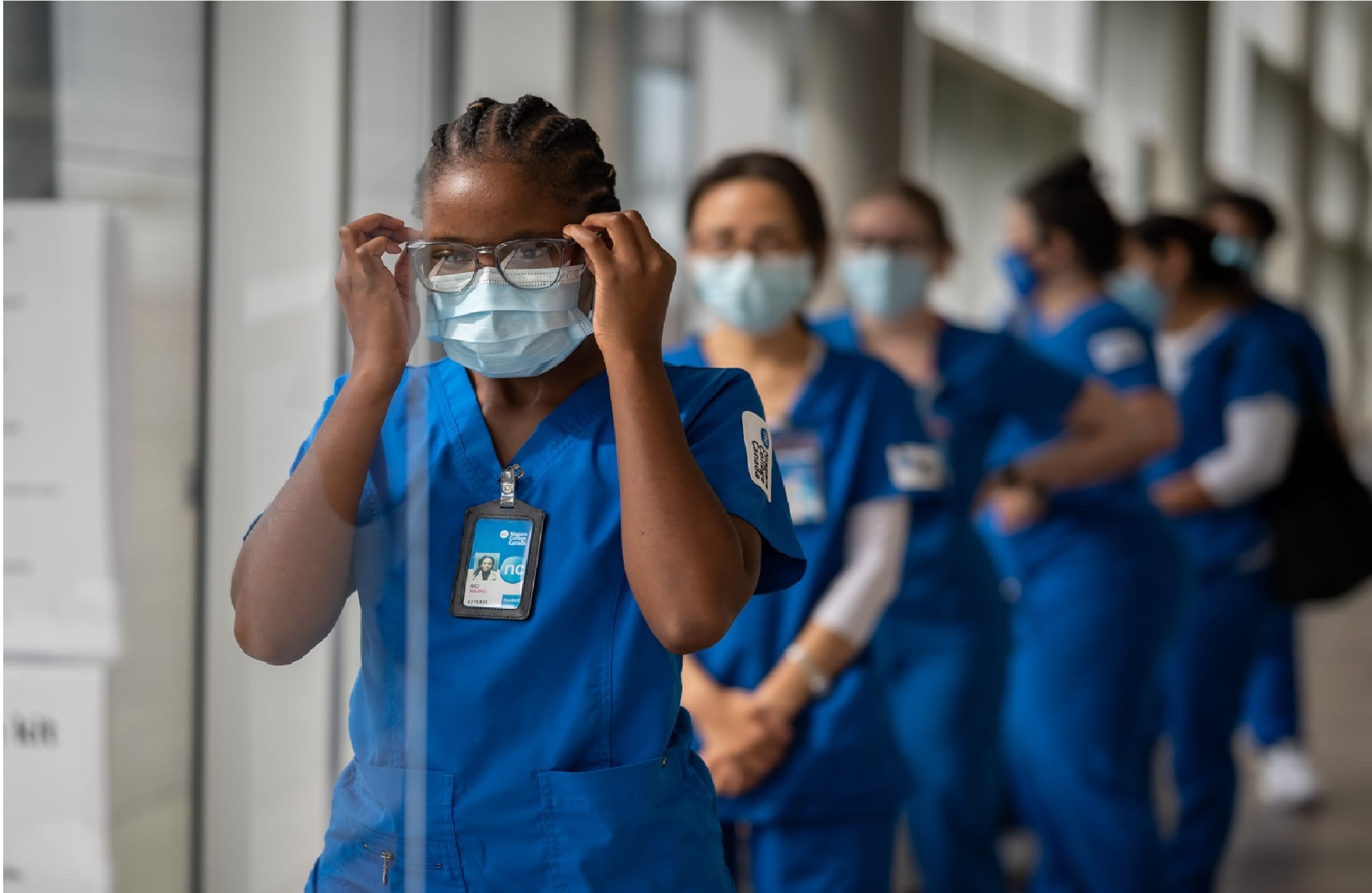 A group of nursing students wearing Niagara College scrubs and face masks lines up.
